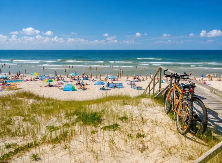 Biciclette parcheggiate su una passerella in legno con vista sulla spiaggia affollata e il mare Adriatico