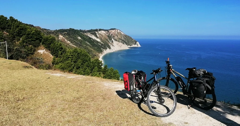 Biciclette da cicloturismo con borse parcheggiate su un belvedere del Promontorio del Conero con vista sul mare Adriatico